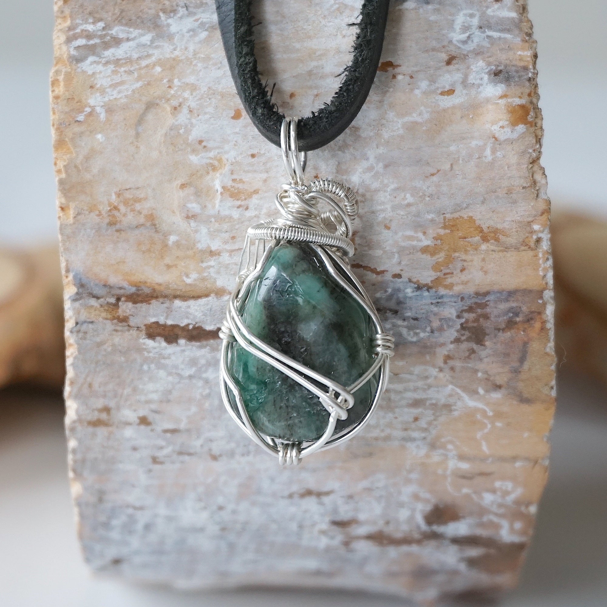 Back view of emerald necklace for men showing detailed sterling silver wire wrapping and natural emerald pendant.