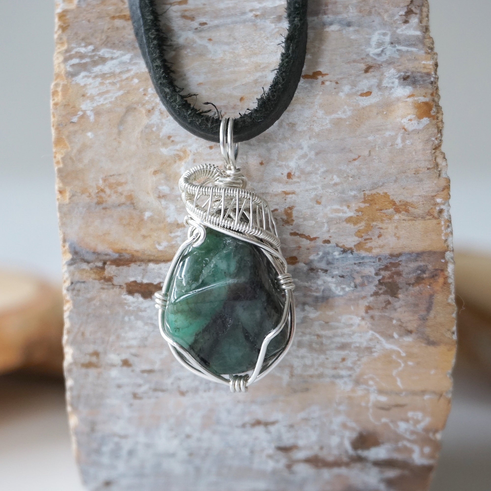 Detailed view of emerald necklace for men with natural polished-raw emerald and 925 sterling silver wire wrapping.