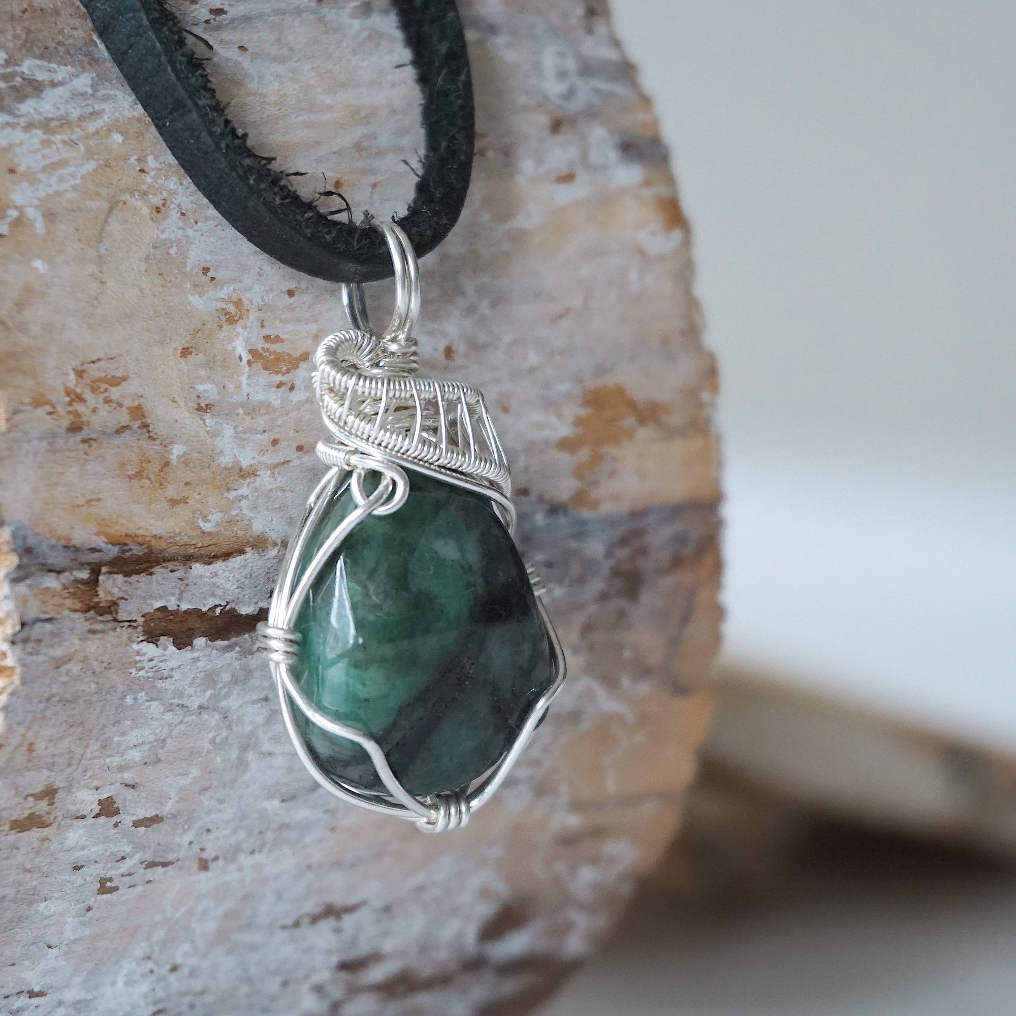 Right angle view of emerald necklace for men showing natural raw emerald and detailed 925 sterling silver wire wrapping.