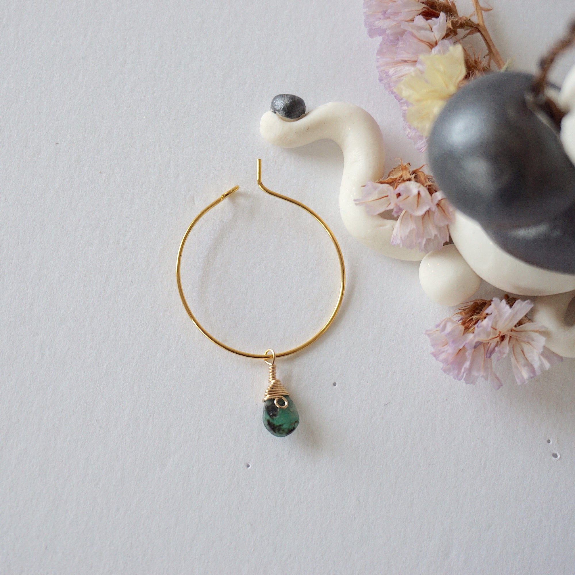 Emerald hoop drop earrings on flat surface showing faceted emerald drop and classic warm gold hoop design