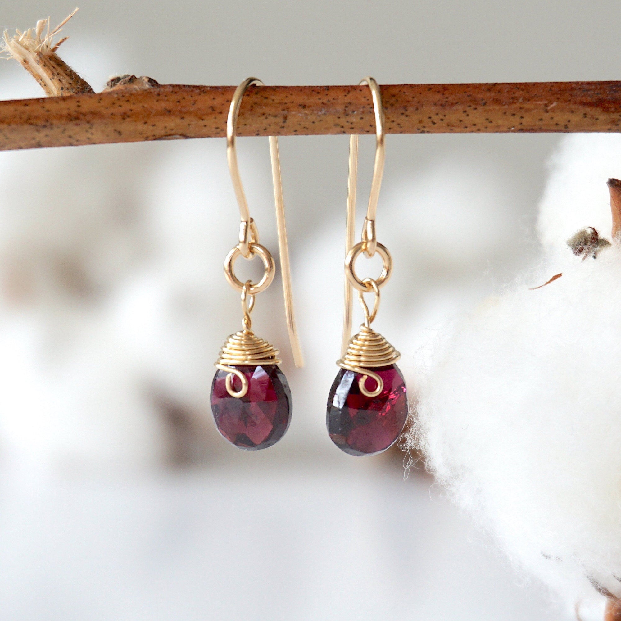 Front view of faceted garnet 14k gold filled drop earrings on display stand, handmade January birthstone dangle earrings