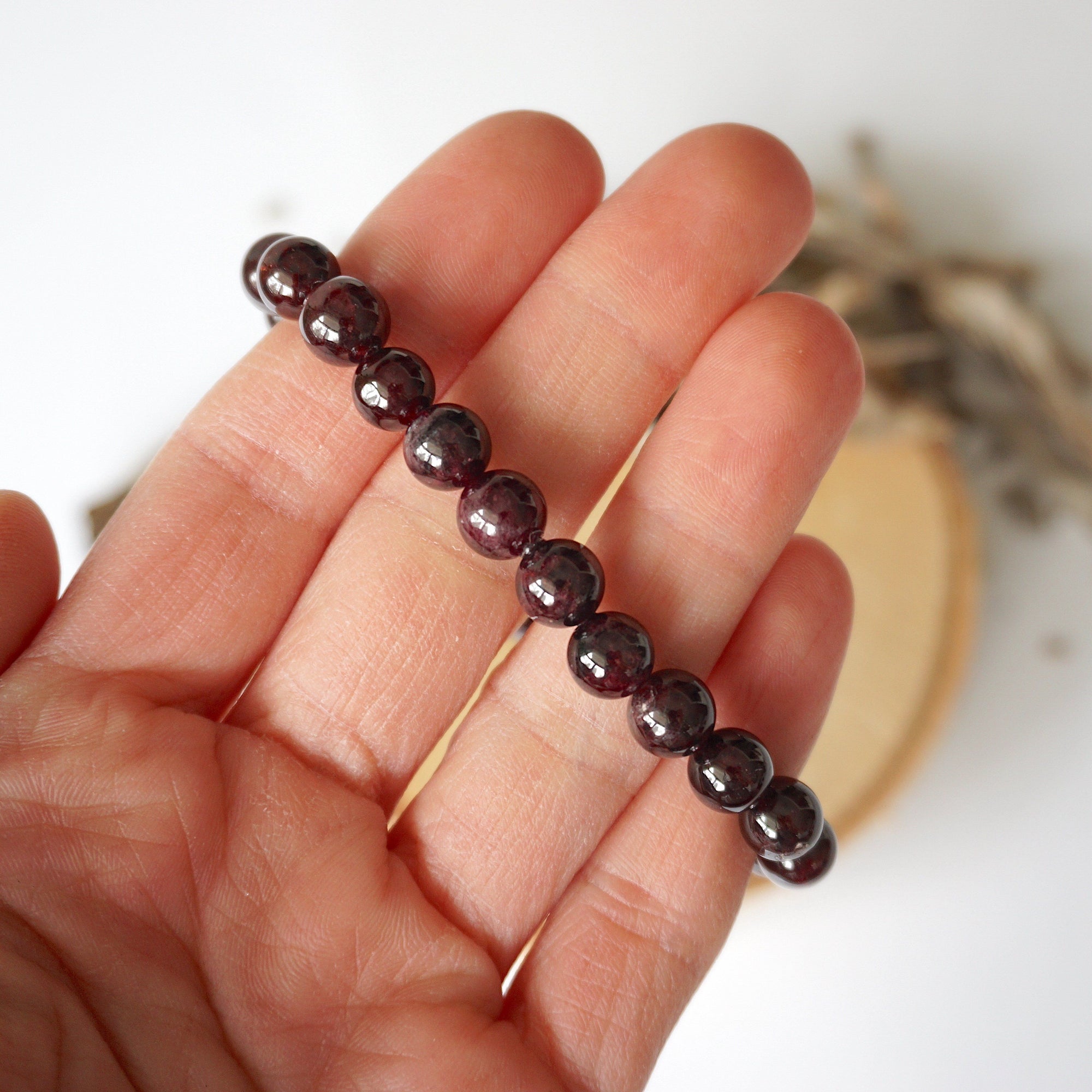 Garnet beaded stretch bracelet shown in hand, highlighting the natural garnet beads and polished finish