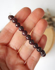 Garnet beaded stretch bracelet shown in hand, highlighting the natural garnet beads and polished finish