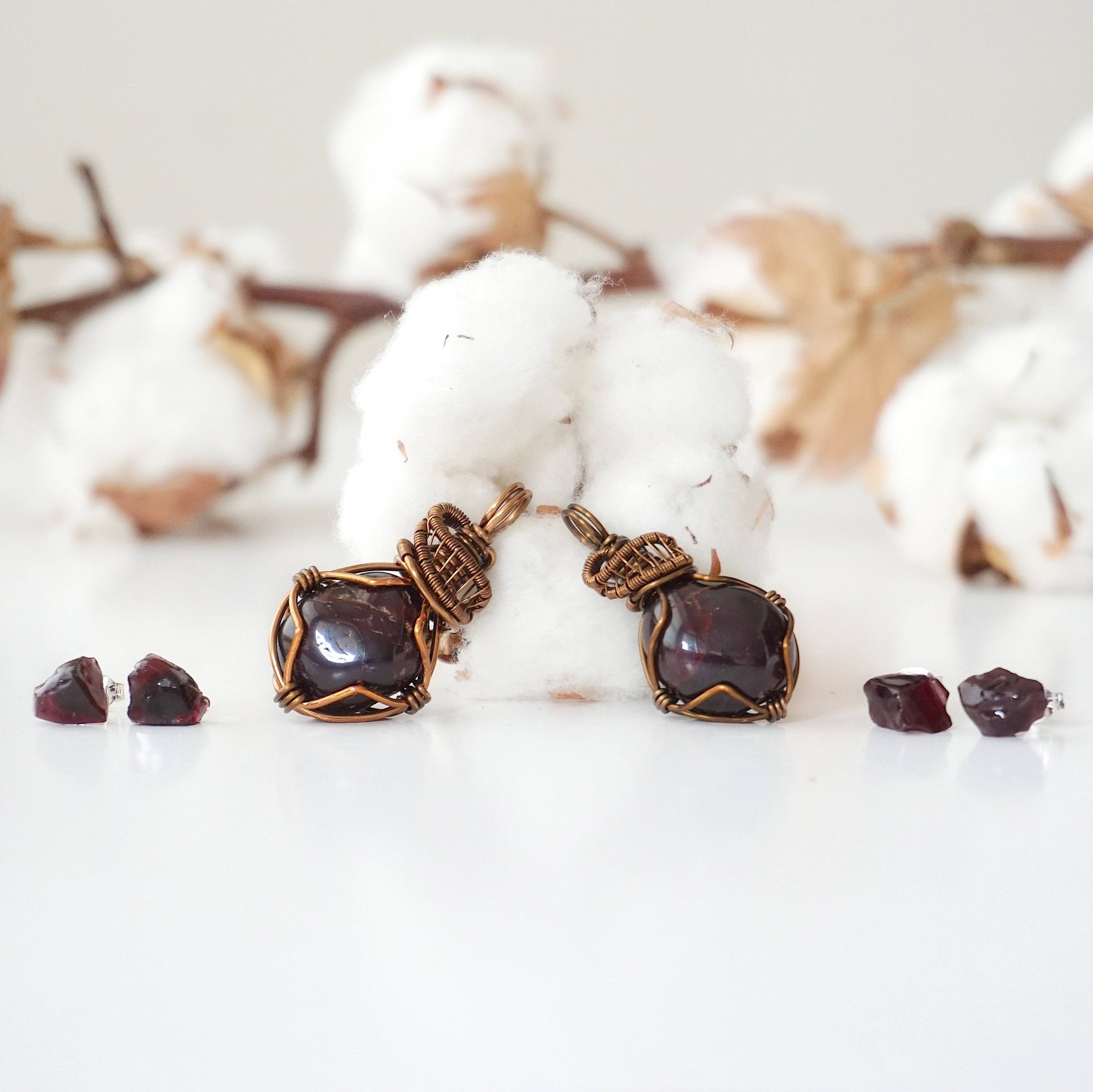 Two garnet pendants and two pairs of garnet stud earrings showing natural variation in size, shape, and color of garnet stones