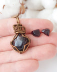 Garnet necklace pendant and stud earrings shown in hand for size reference, featuring natural garnet stones