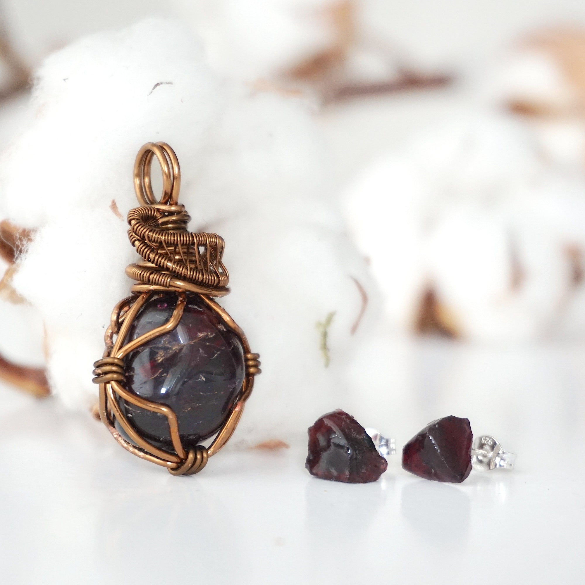Front view of a garnet necklace and stud earrings jewelry set with an antique bronze wire wrapped pendant and sterling silver garnet studs