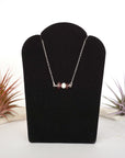 Garnet and freshwater pearl bar necklace in 925 sterling silver on jewelry display, front view