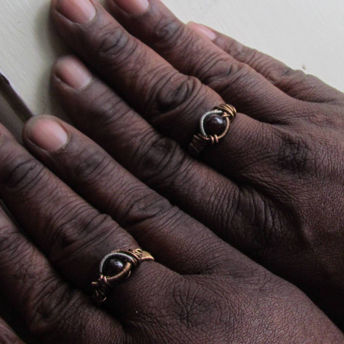Gender neutral wire wrapped garnet ring shown on female and male hands to demonstrate fit and scale