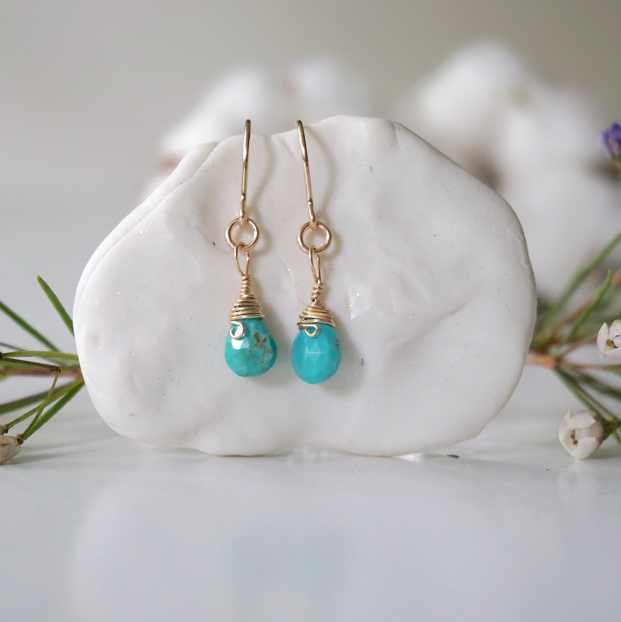 Gold turquoise drop earrings with wire wrapped crystal beads hanging on display, front view showing detailed craftsmanship