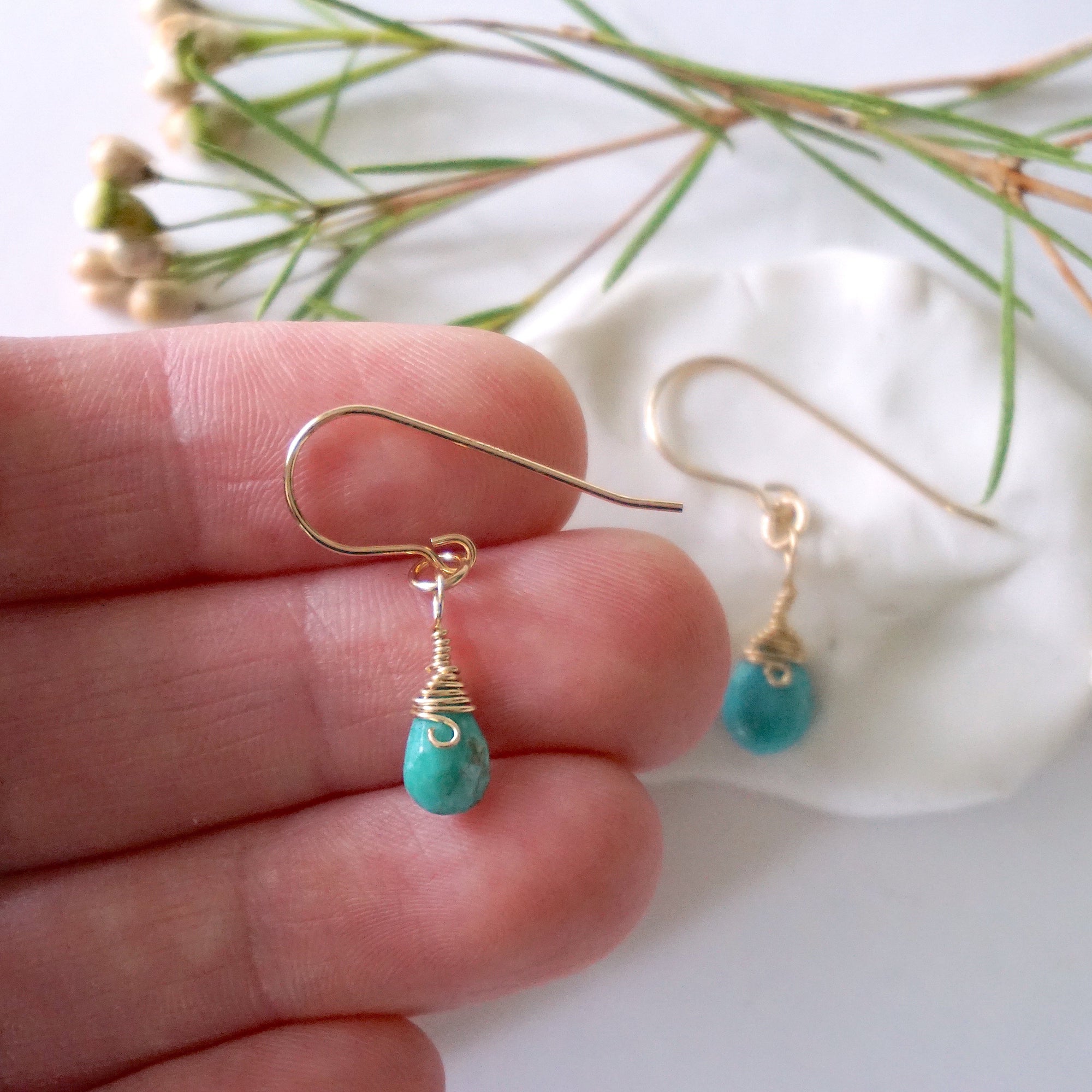 Gold turquoise dangle earrings held in hand showing size and length of handmade wire wrapped crystal drop earrings