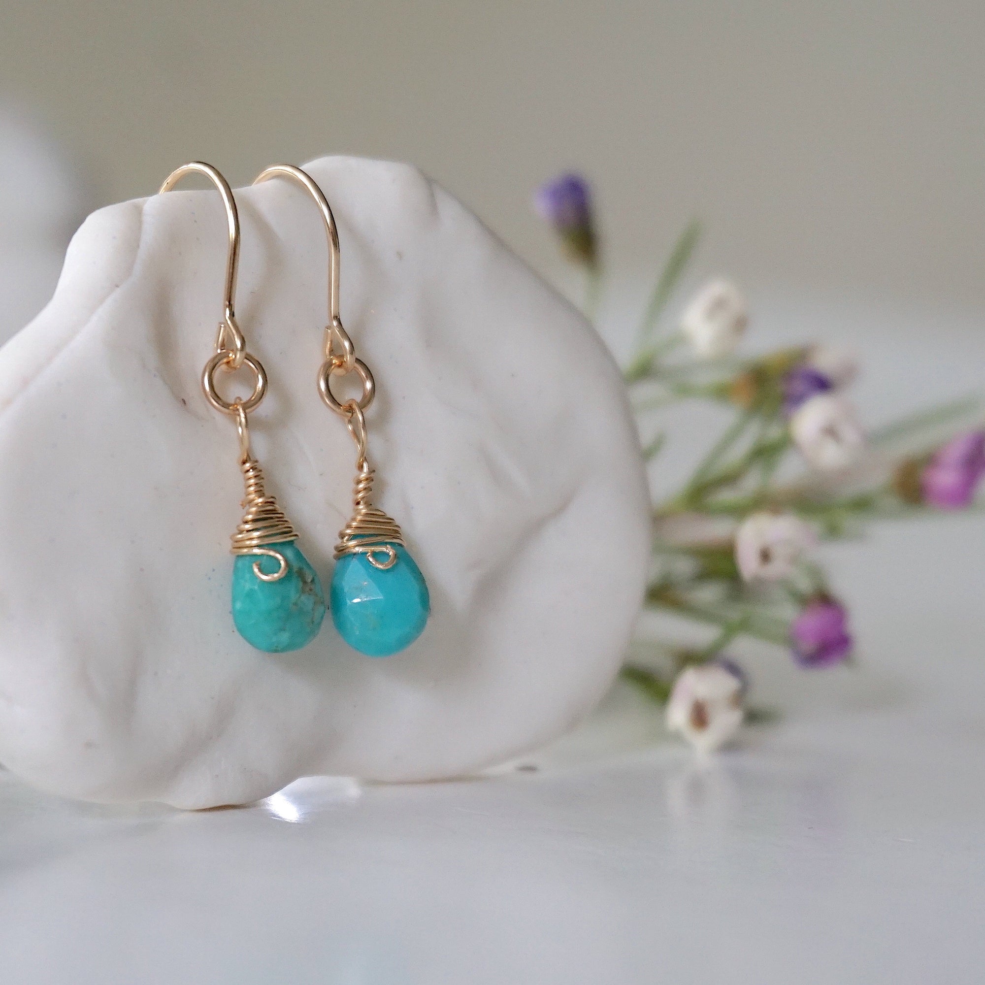 Right side view of gold turquoise drop earrings on display showing wire wrapping detail and natural crystal facets