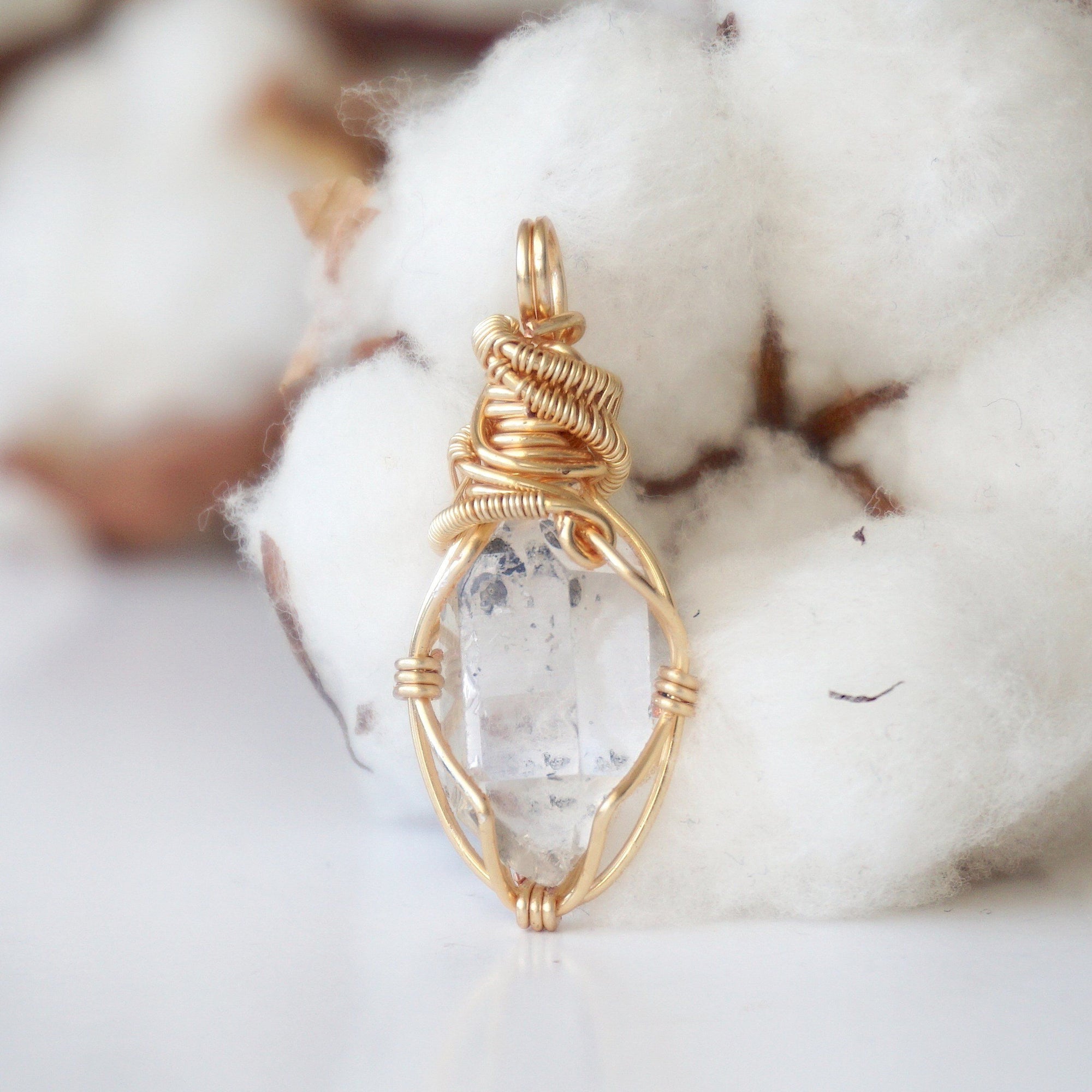Back angle detail of raw Herkimer diamond pendant with intricate artisan wire wrapping in warm gold copper.