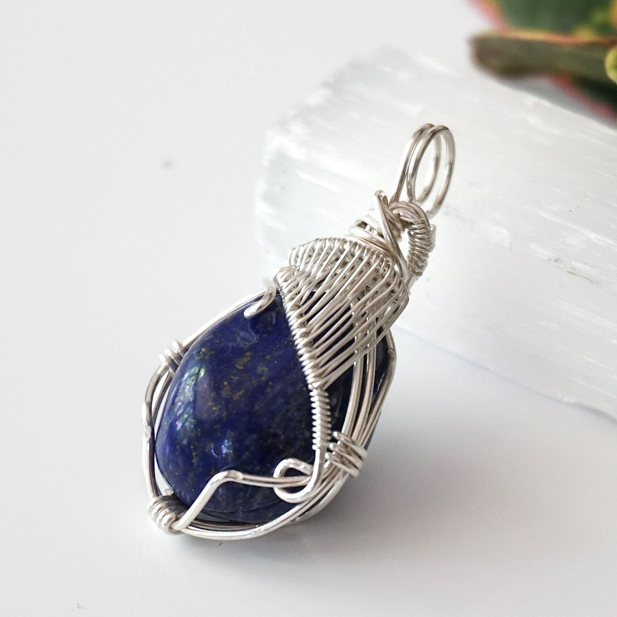 Side view of a lapis lazuli pendant showing the depth of the stone and its sterling silver wire wrap