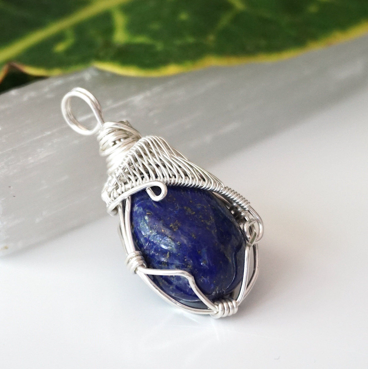Angled view of the handmade sterling silver bail and woven wire wrap on a lapis lazuli pendant