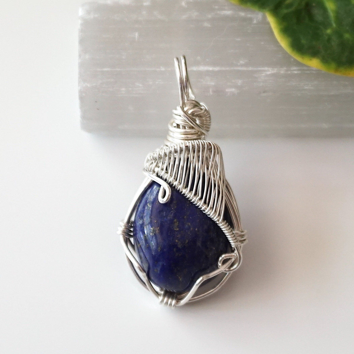 Front view of a deep blue lapis lazuli pendant with gold pyrite flecks, wrapped in sterling silver