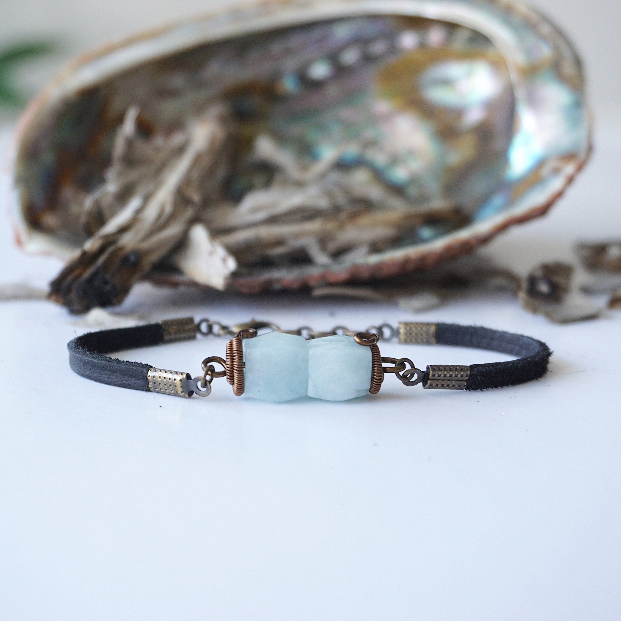 Detailed front angle of men's aquamarine bracelet, genuine faceted aquamarine, artisan wire wrapping, antique bronze finish, black leather