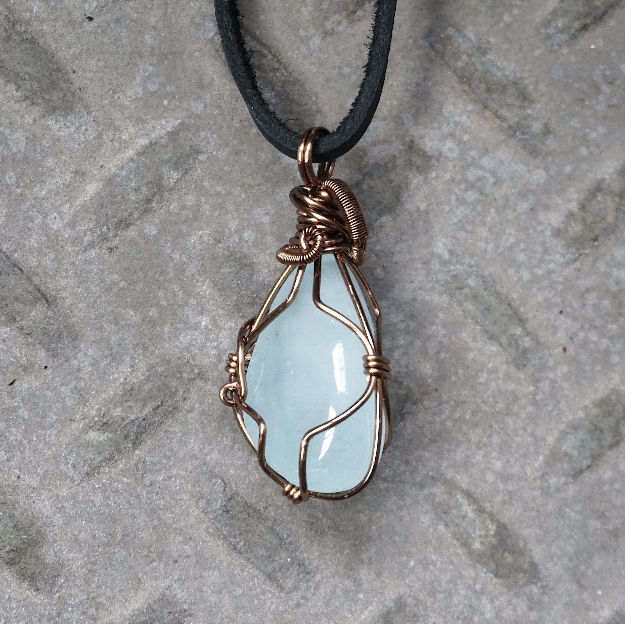 Back side angle of men's aquamarine pendant necklace, detailed wire wrapping, antique bronze copper, black leather cord