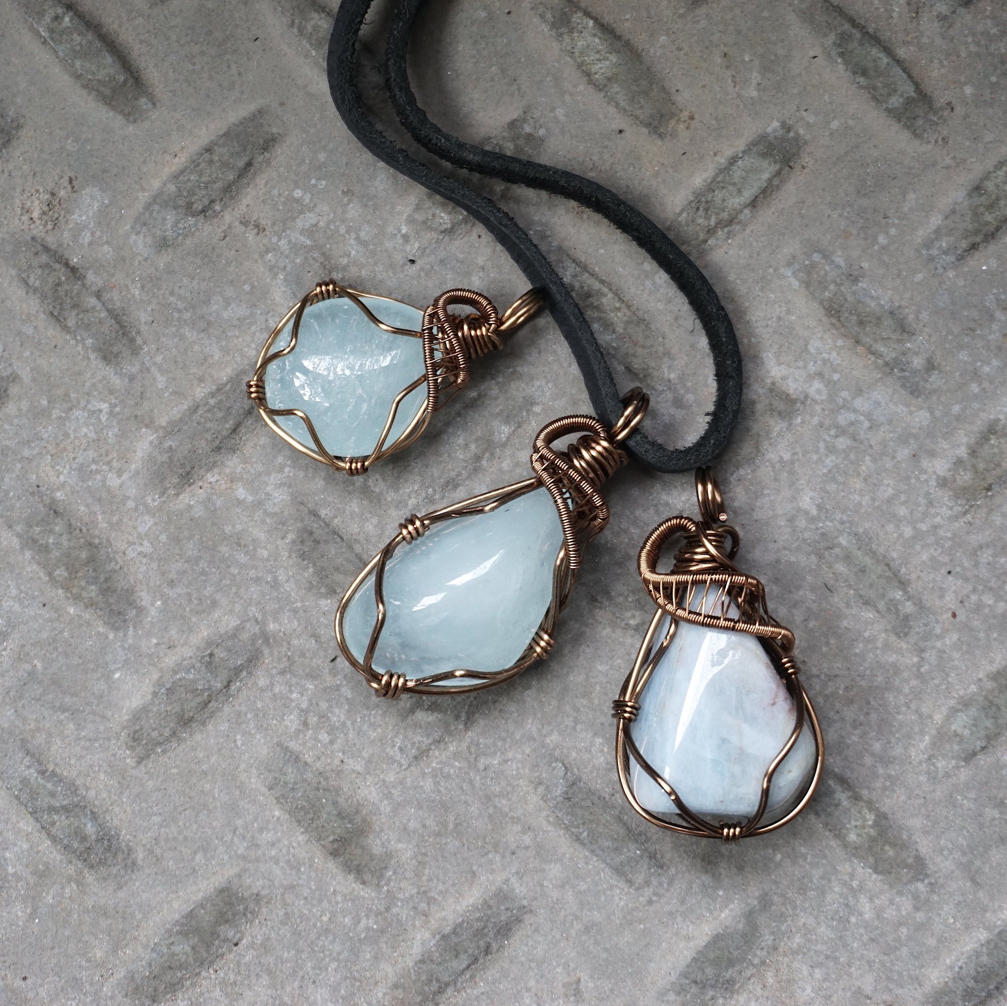 Three men's aquamarine pendants showing natural variation in aquamarine's shape, size, and blue color, Designs by Nature Gems