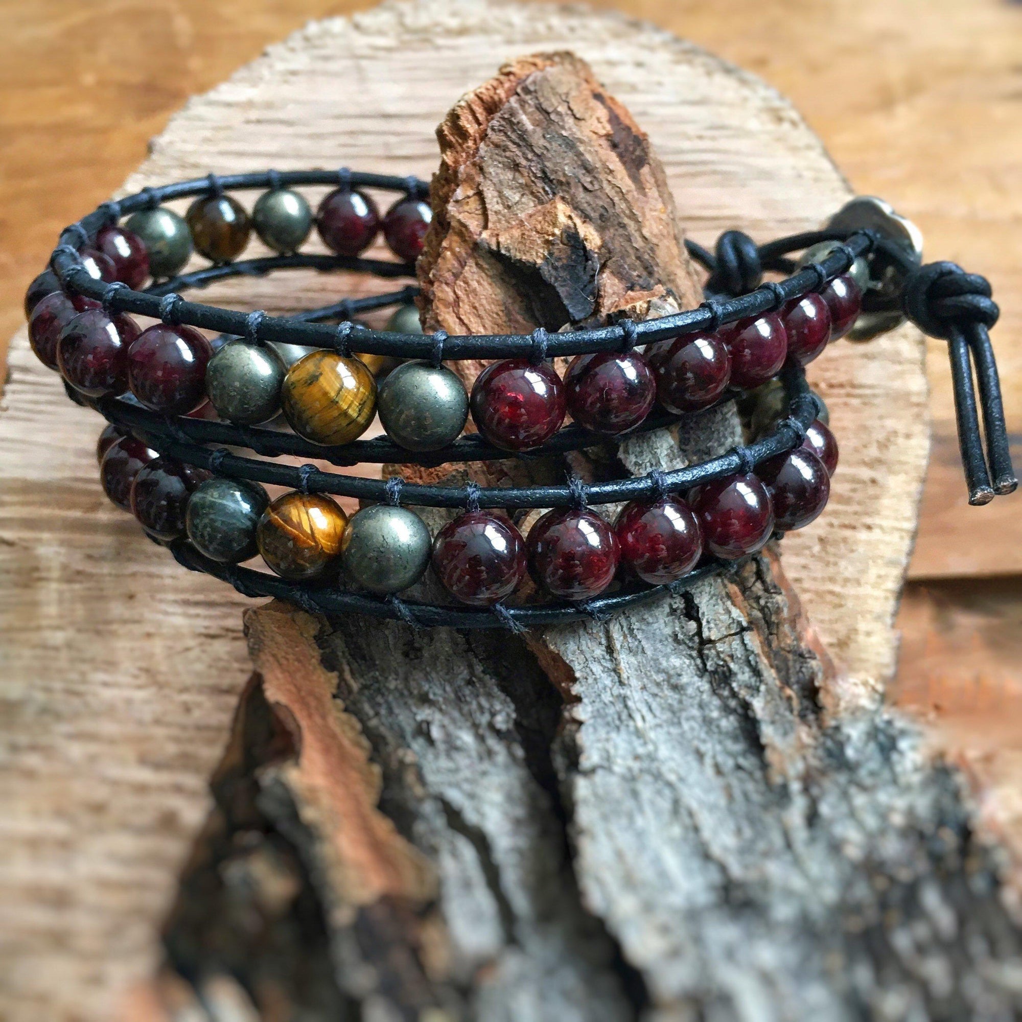 Angled view of a men’s leather wrap beaded bracelet with garnet as the dominant stone, accented with tiger’s eye and pyrite