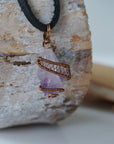 Right side view of raw amethyst crystal pendant wire wrapped in antique bronze copper on black leather cord, men’s necklace