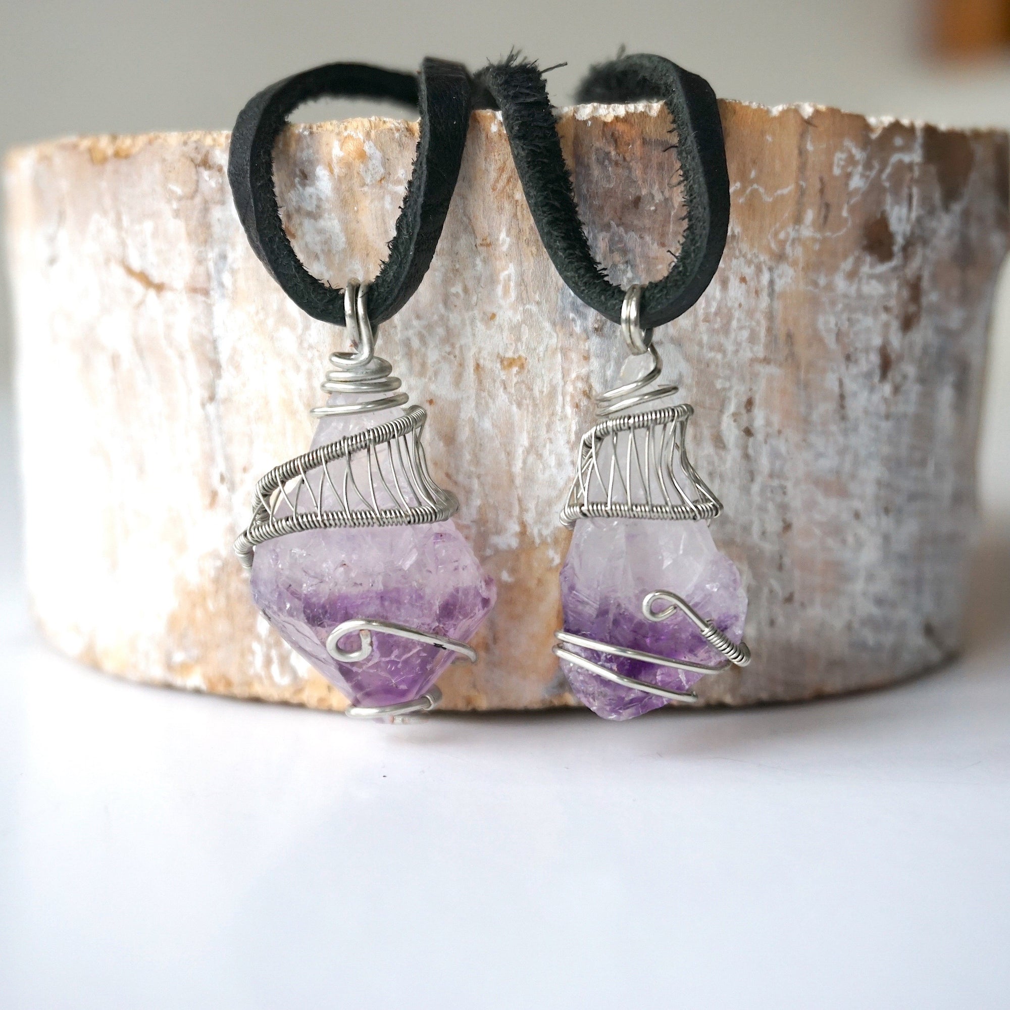 Two men’s raw amethyst pendant necklaces on black leather cord showing natural variation in amethyst size, shape, and color