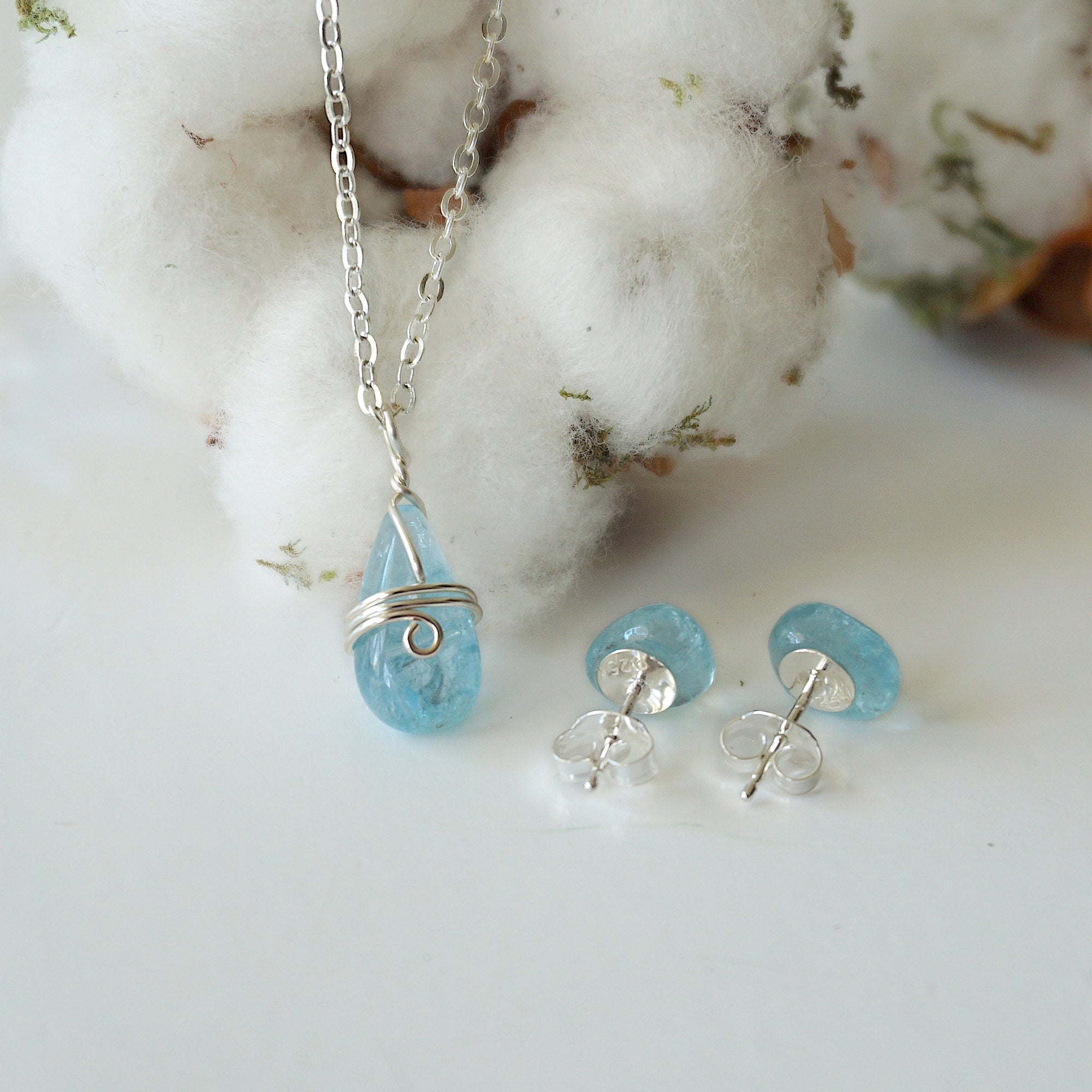 Front angle view of aquamarine necklace and back side of earrings, soft silver wire wrapped pendant and sterling silver stud earrings, March birthstone