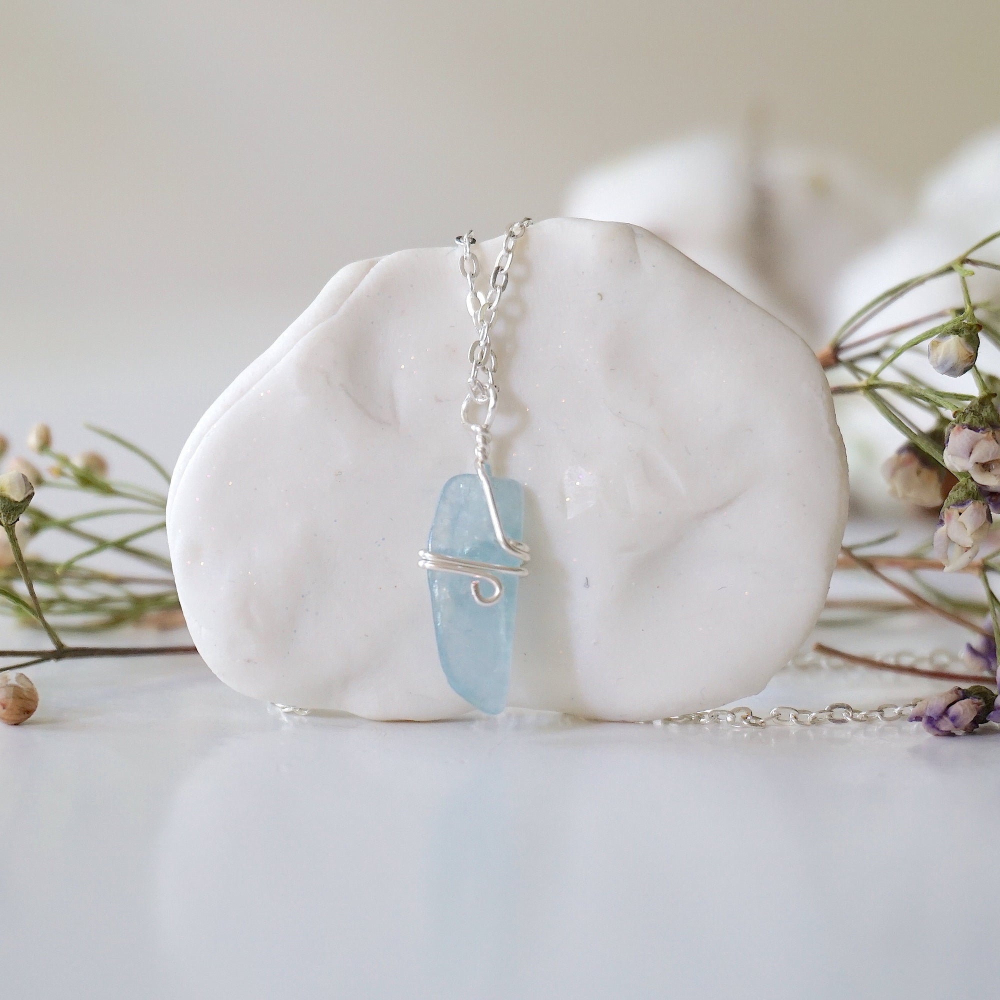 Back side angle of minimalist aquamarine necklace, showing simple wire wrapping and silver plated chain