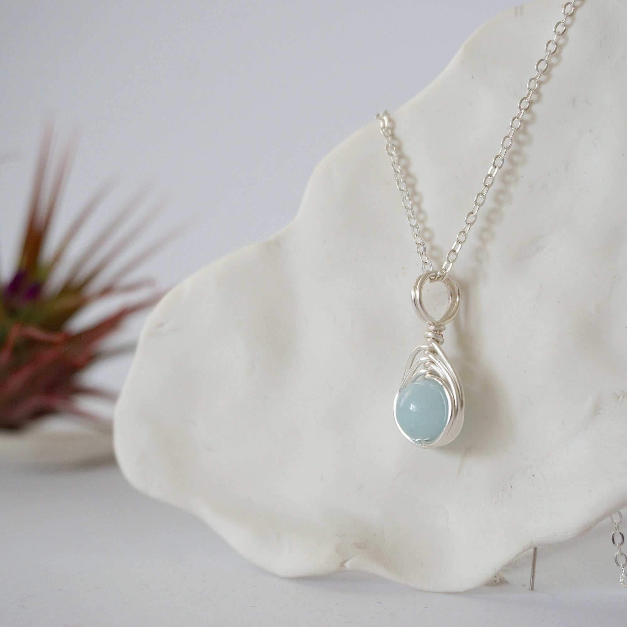 Side angle of minimalist aquamarine necklace, showing soft silver finish wire wrapping and natural aquamarine bead