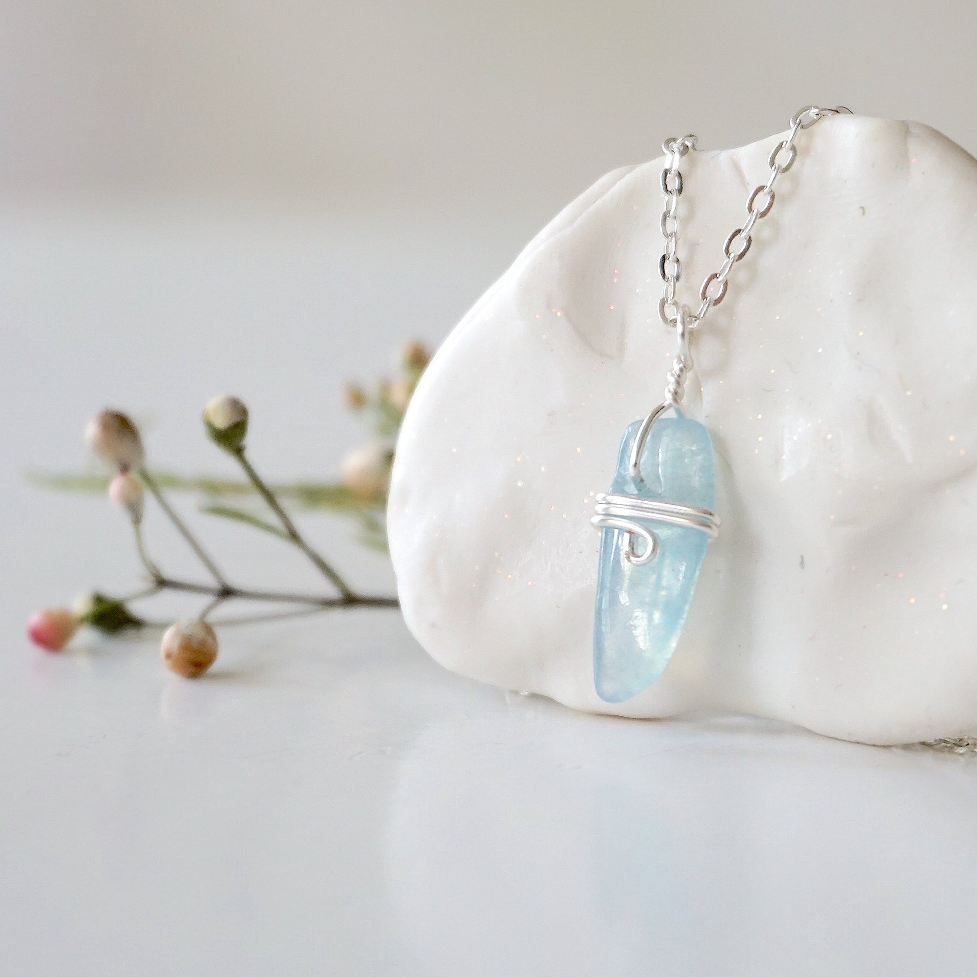 Left side angle of minimalist aquamarine necklace, polished aquamarine pendant, soft silver wire wrapping