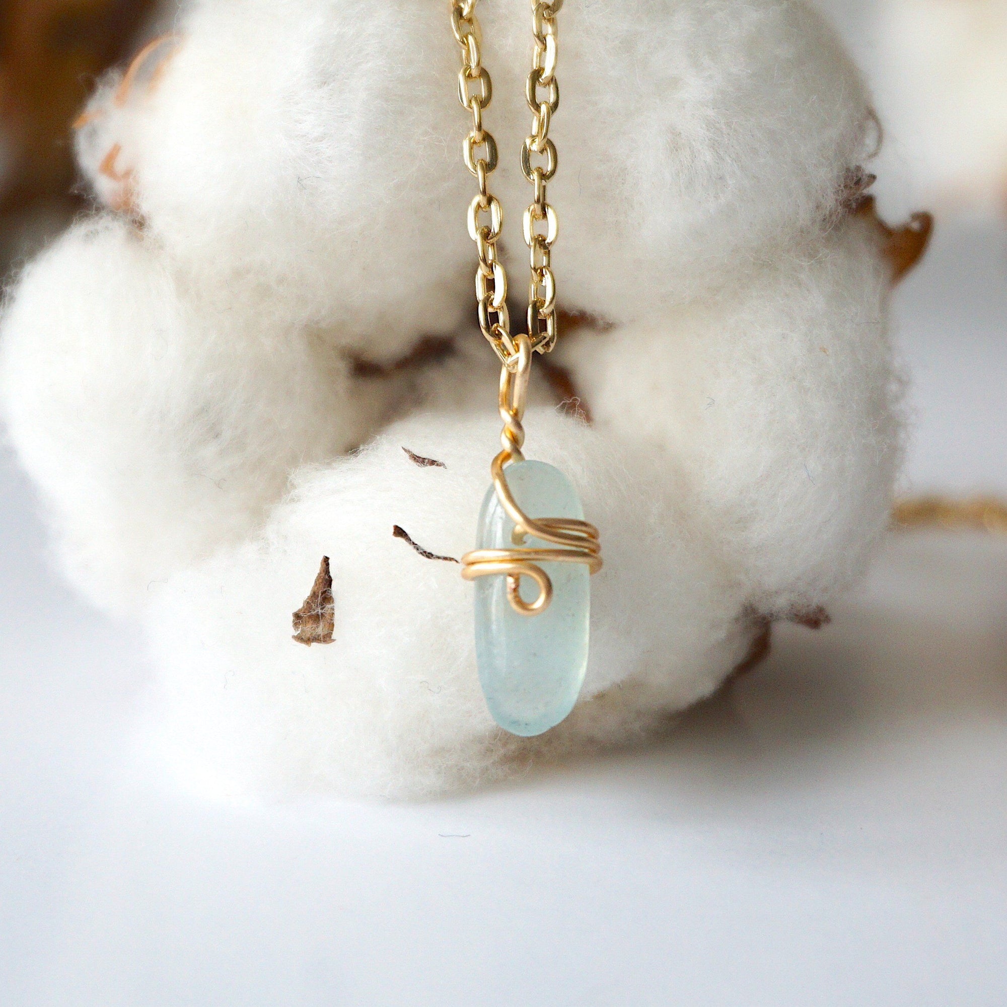 Back side angle of minimalist aquamarine necklace, showing simple wire wrapping and gold plated chain