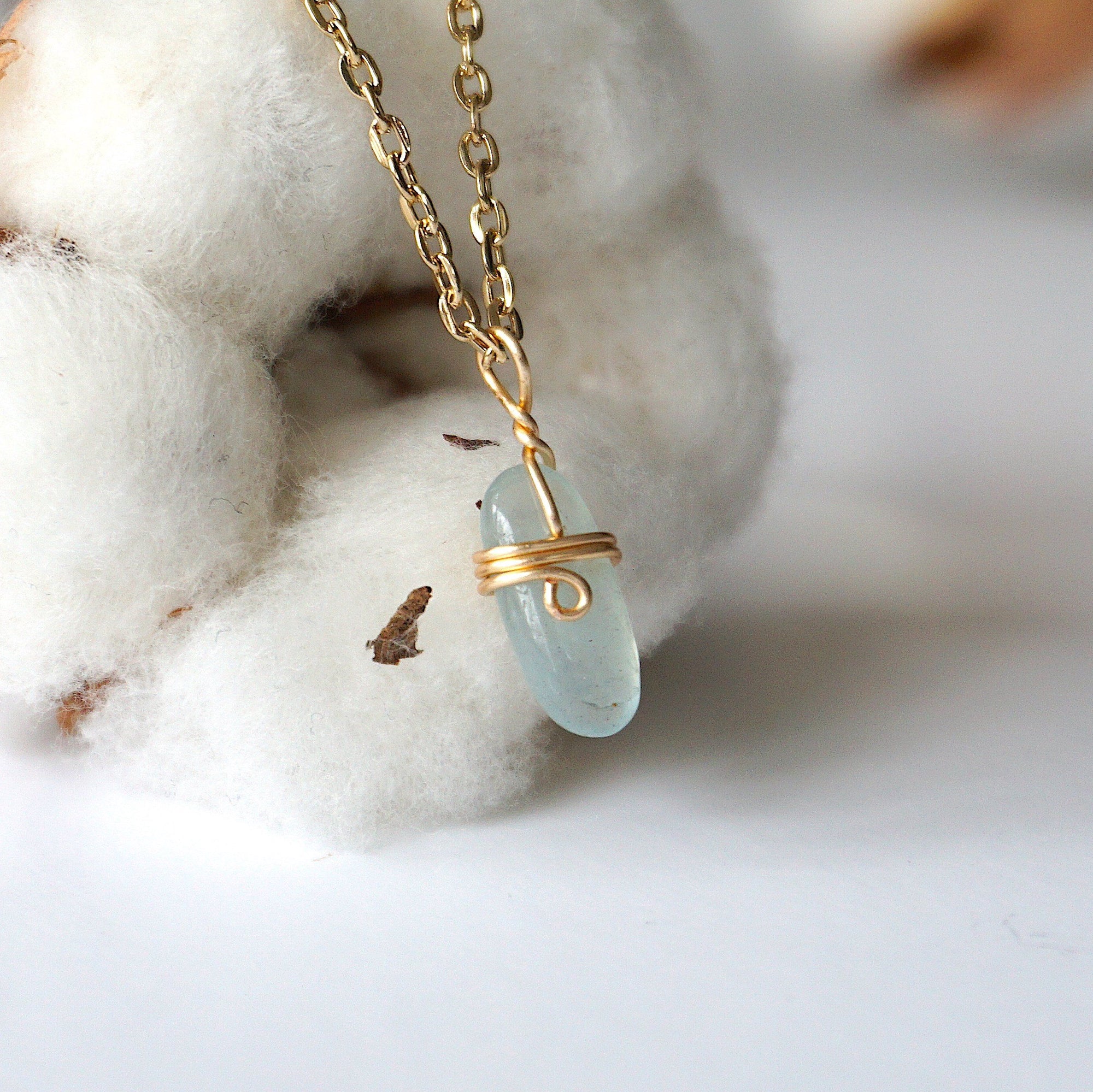 Right side angle of minimalist aquamarine necklace, showing genuine aquamarine pendant and warm gold finish over copper wire