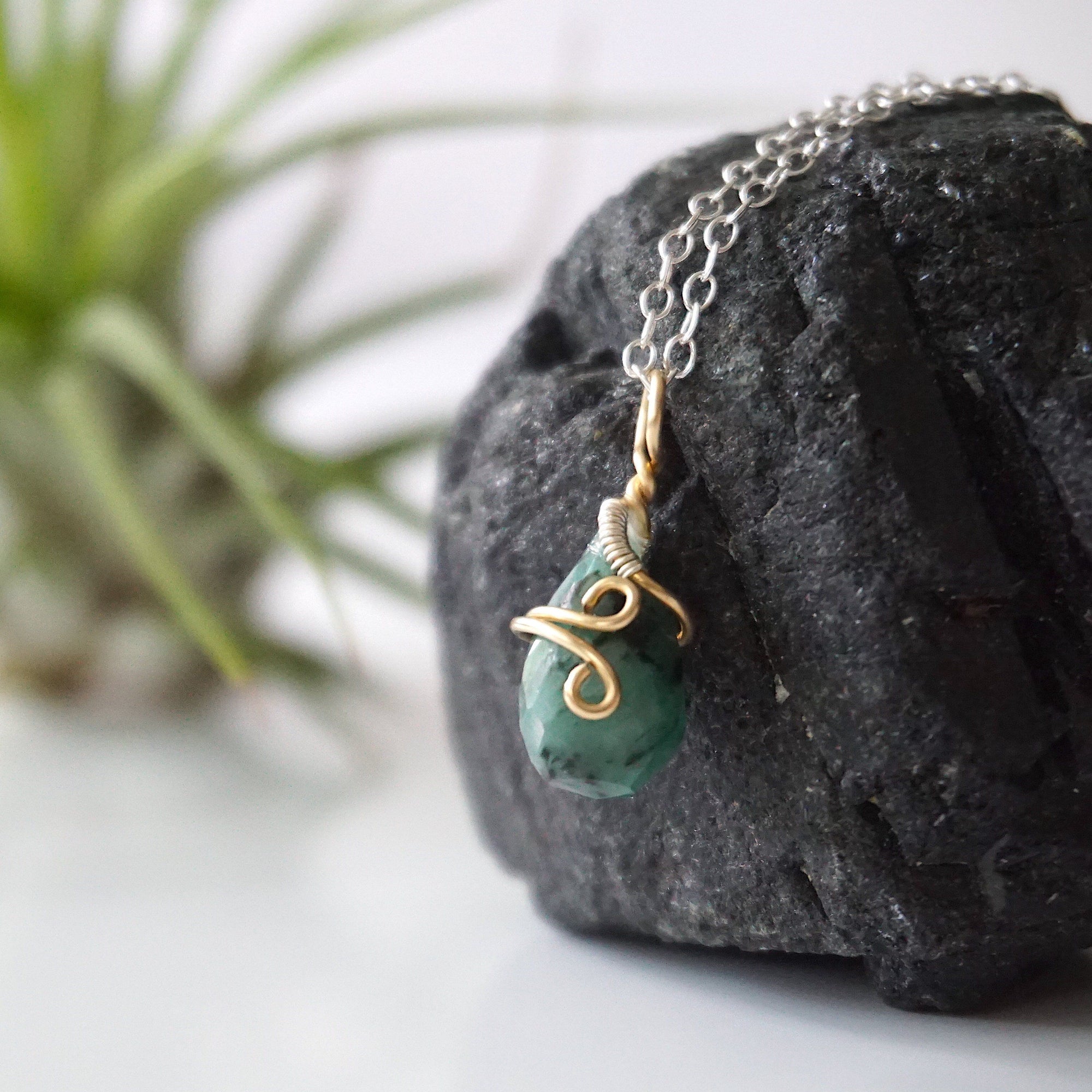 Left angle detail of emerald necklace for women with natural faceted teardrop emerald and artisan mixed metal wire wrapping