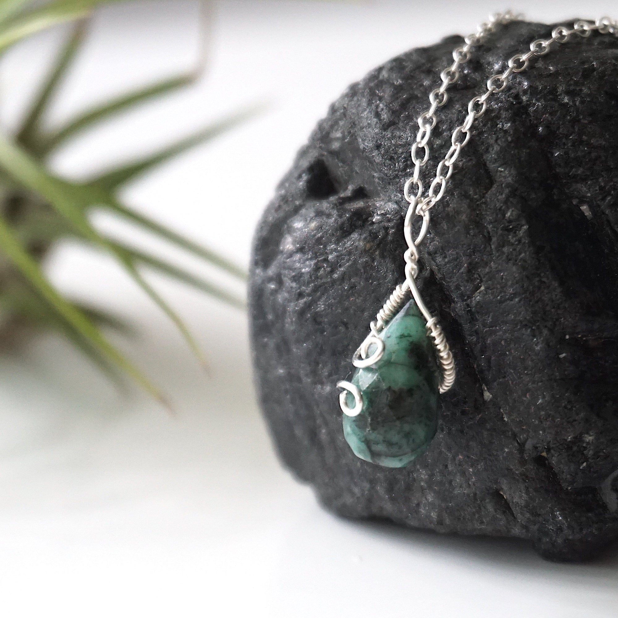 Left angle detail of emerald necklace for women with natural faceted emerald and artisan sterling silver wire wrapping