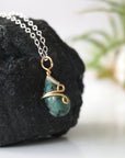 Right angle detail of minimalist emerald pendant for women with natural faceted emerald in 14k gold filled and sterling silver wrapping