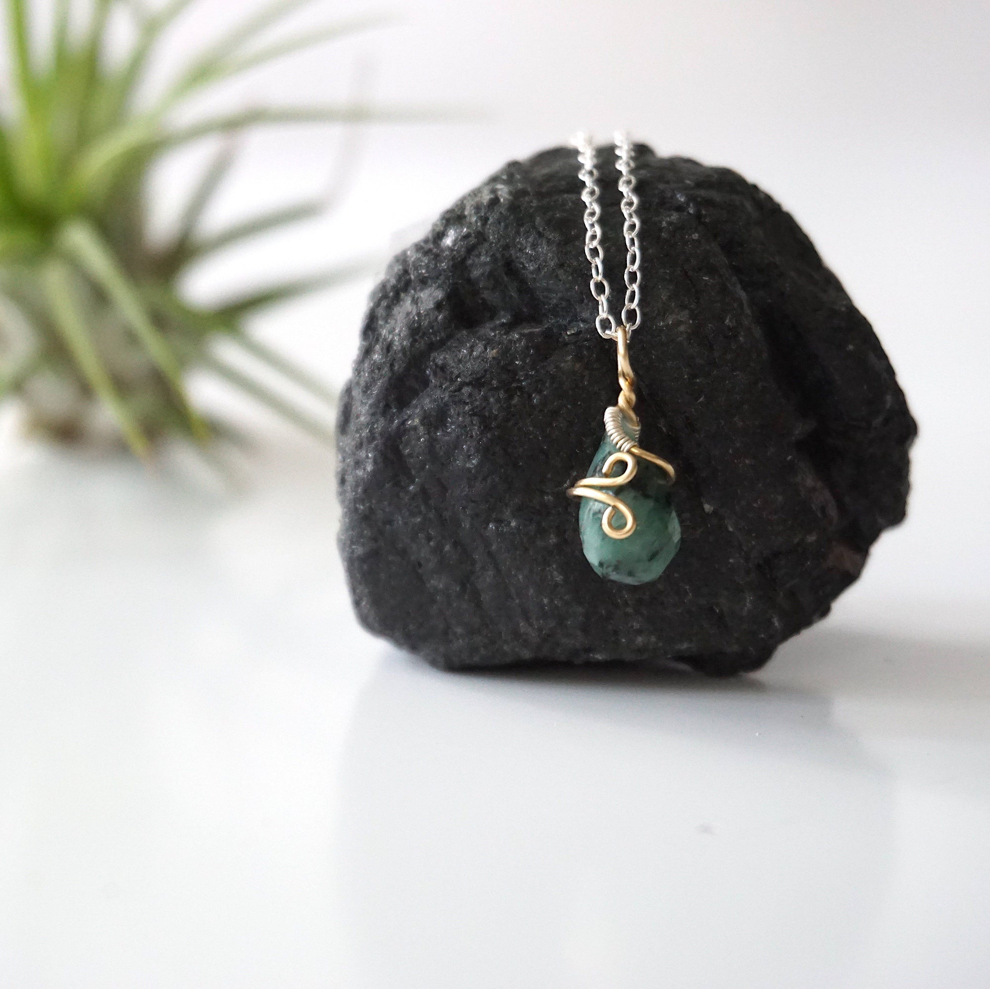Zoomed out view of minimalist emerald necklace for women with faceted teardrop emerald on sterling silver chain