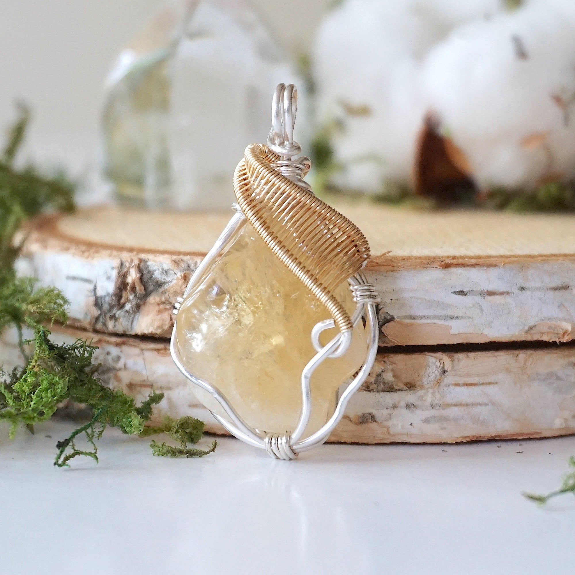 Natural raw citrine stone detail in silver gold wire wrapped pendant - unpolished yellow crystal healing gemstone jewelry closeup