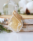 Natural raw citrine stone detail in silver gold wire wrapped pendant - unpolished yellow crystal healing gemstone jewelry closeup