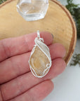 Natural citrine pendant held in hand showing size scale - wire wrapped crystal in silver plated copper handmade necklace size reference minimalist jewelry