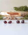 Two pairs of natural garnet stud earrings in sterling silver showing unique stone variation in size, shape, and deep red tone