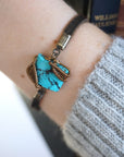Natural turquoise bracelet with antique bronze wire wrapping on genuine leather strap worn by woman, December birthstone jewelry