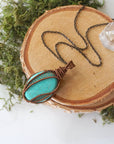 Natural turquoise necklace for women with intricate antique bronze wire wrapped pendant on 24 inch chain laying flat