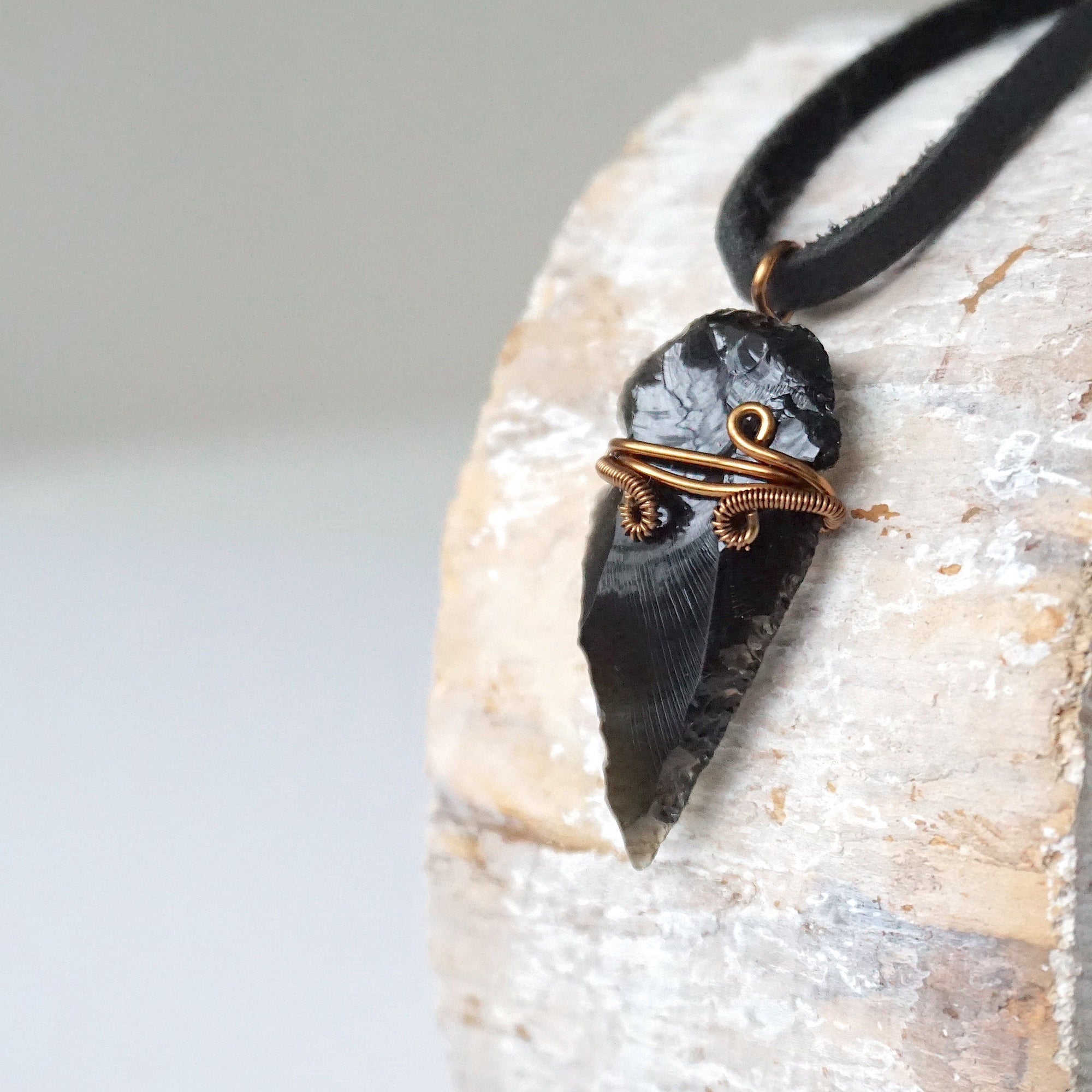 Side angle detail of men’s black obsidian arrowhead necklace, antique bronze copper wire wrap, on black leather cord by Designs by Nature Gems.