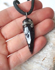 Black obsidian arrowhead necklace for men shown on black leather cord in a hand for size reference, natural crystal jewelry by Designs by Nature Gems.