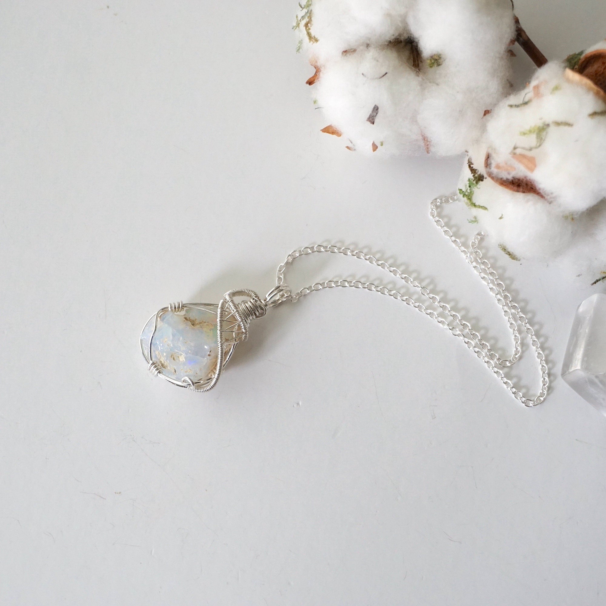 Sterling silver opal pendant on chain laying flat, handcrafted jewelry by Designs by Nature Gems.