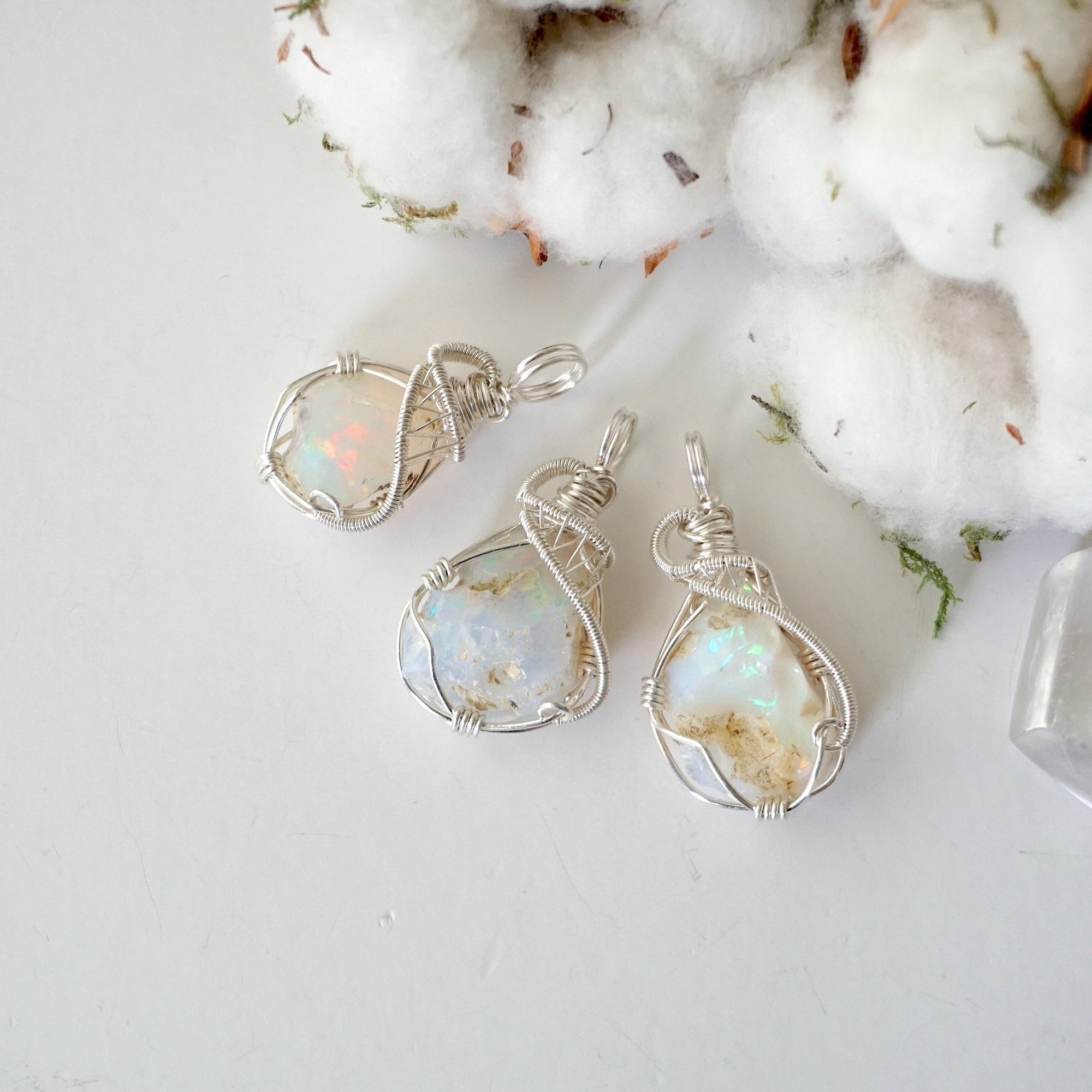 Three sterling silver opal pendants showing natural stone variation in size, shape, and color, artisan jewelry by Designs by Nature Gems.