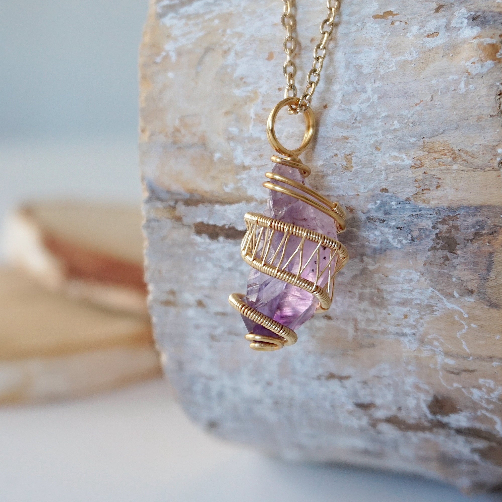 Left side detail of raw amethyst point pendant necklace with gold plated copper wire wrap on gold plated brass chain