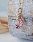Left side detail of raw amethyst point pendant necklace with gold plated copper wire wrap on gold plated brass chain