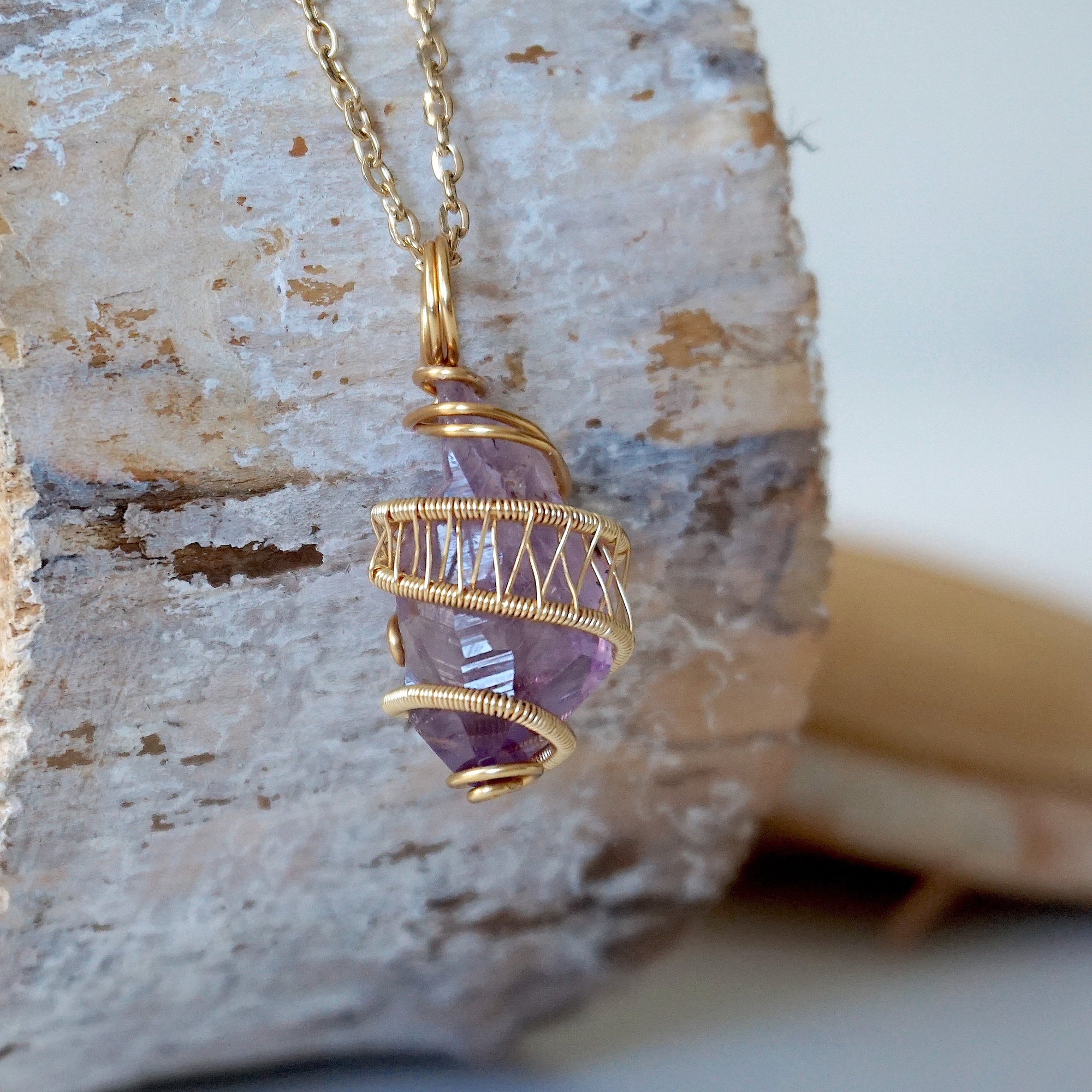 Right side detail of raw amethyst point pendant with intricate gold plated copper wire wrapping on gold plated brass chain