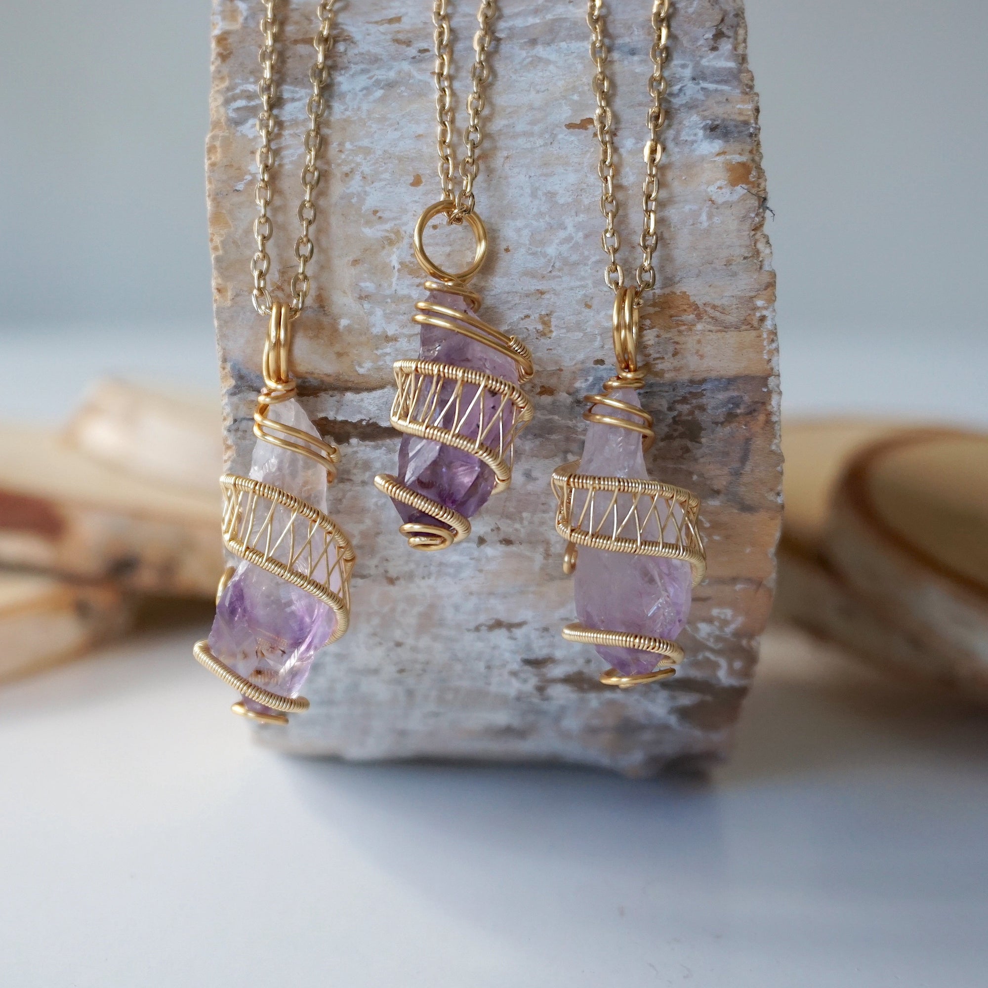 Three raw amethyst point pendant necklaces on gold plated brass chain showing natural variation in crystal color, size, and shape