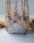 Three raw amethyst point pendant necklaces on gold plated brass chain showing natural variation in crystal color, size, and shape